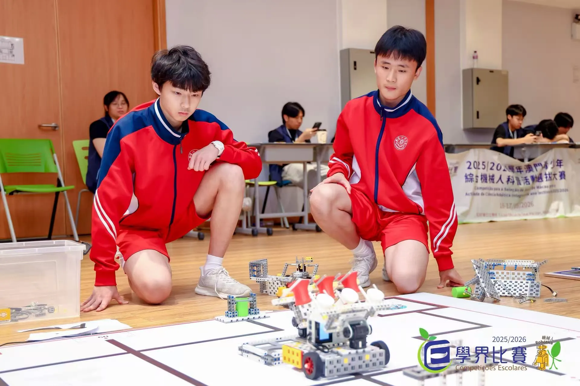 Noah and a teammate observing robots on a school competition floor